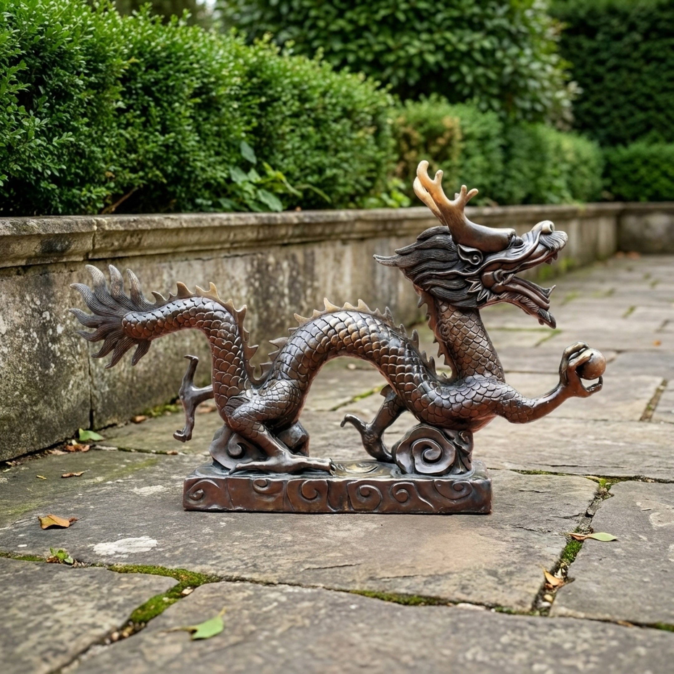 Large Traditional Coiling Chinese Dragon Bronze Sculpture by Giant Sculptures shown in profile on a stone patio, gripping a sphere with gold-toned horns.