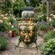 Large Traditional Gilded Buddha Head Bronze Sculpture by Giant Sculptures on a stone path, surrounded by roses, lavender, and hostas in a walled garden.