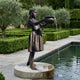 Large Traditional Girl Holding Bird Bath Bronze Fountain by Giant Sculptures, 190cm barefoot girl in dress pouring water from a bowl beside a garden pool.