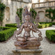 Large Traditional Green Tara Goddess Bronze Sculpture by Giant Sculptures, 180cm, seated on a lotus throne with lotus stems, displayed in a garden courtyard.