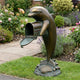 Large Traditional Leaping Dolphin Mailbox Bronze Sculpture by Giant Sculptures on a garden path, mailbox door open, beside lavender and roses.