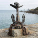Large Traditional Naval Anchor Bronze Sculpture by Giant Sculptures, 200cm, dark patinated admiralty anchor wrapped in rusted chain on a stone block by the sea.