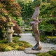 Giant Sculptures Large Traditional Pelican in Flight Bronze Sculpture with wings raised on a rock base, set on a gravel path in a Japanese garden.