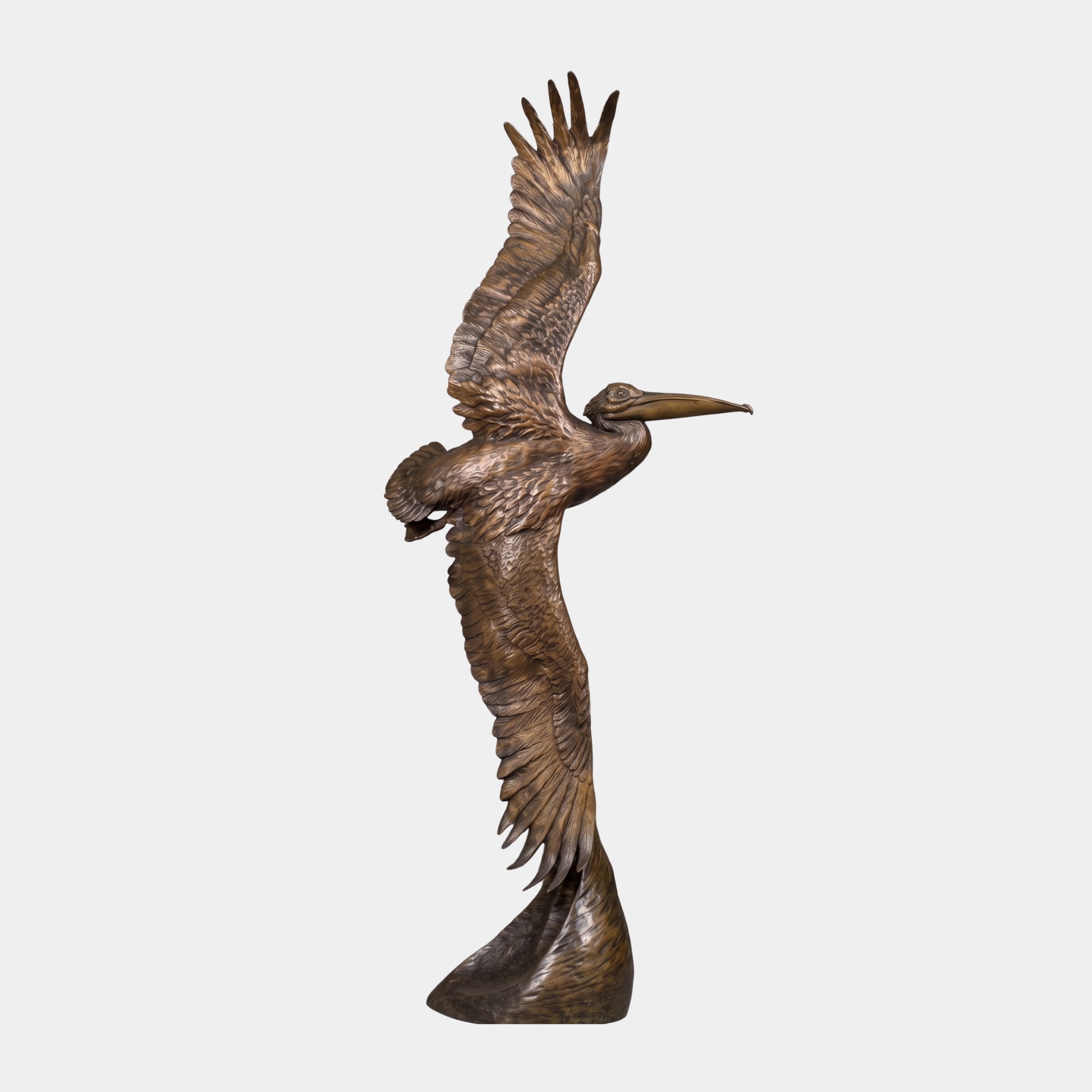 Large Traditional Pelican in Flight Bronze Sculpture by Giant Sculptures, side view with wings raised and bill forward, warm brown patina, on naturalistic base.