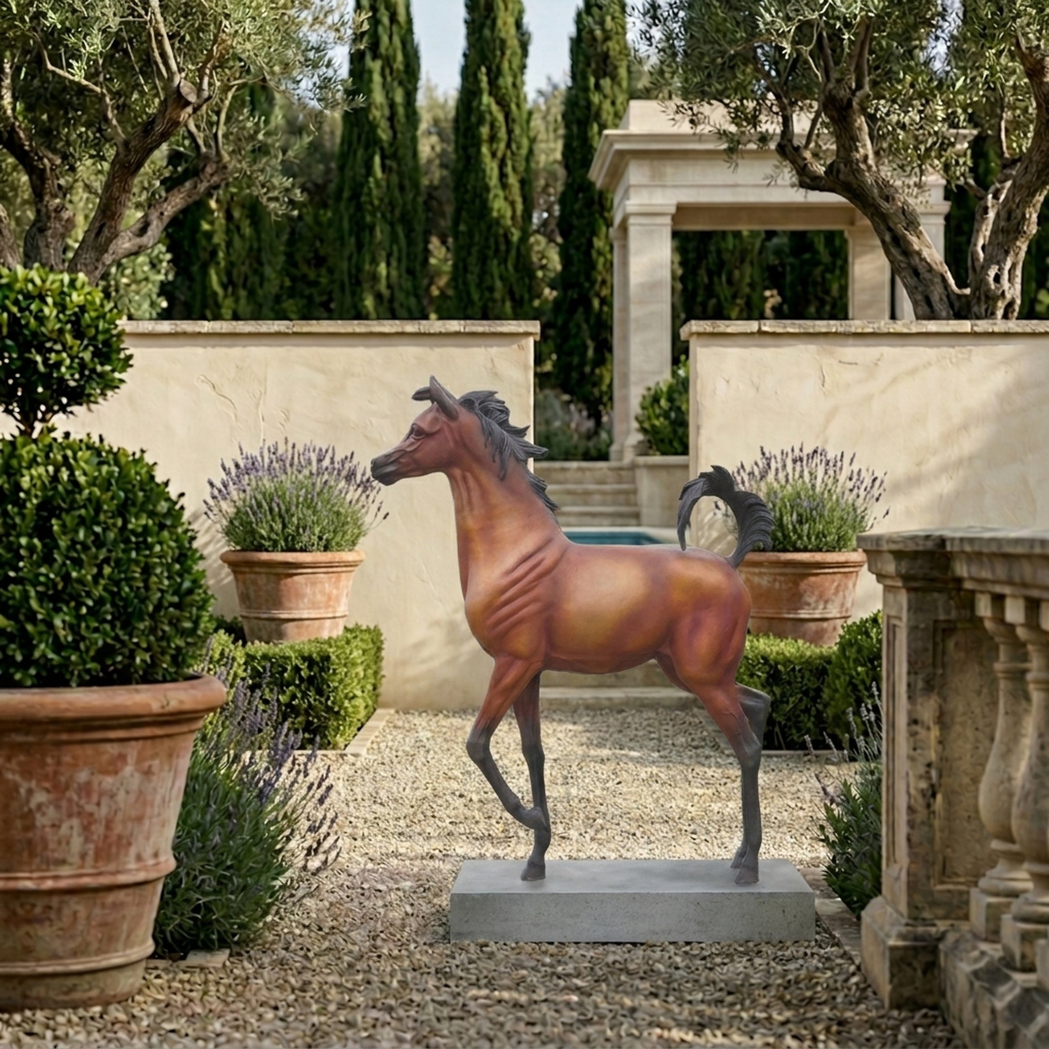 Large Traditional Prancing Arabian Horse Bronze Sculpture by Giant Sculptures on a grey plinth in a Mediterranean garden with lavender, topiary, and cypress trees.