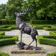 Large Traditional Rearing Stag Bronze Sculpture by Giant Sculptures, dark patinated stag with raised head and antlers on a rocky base, set in a formal hedged garden.