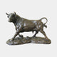 Large Traditional Striding Bull Bronze Sculpture by Giant Sculptures, side view with lowered head, raised front leg, and curled tail on a rocky bronze base.