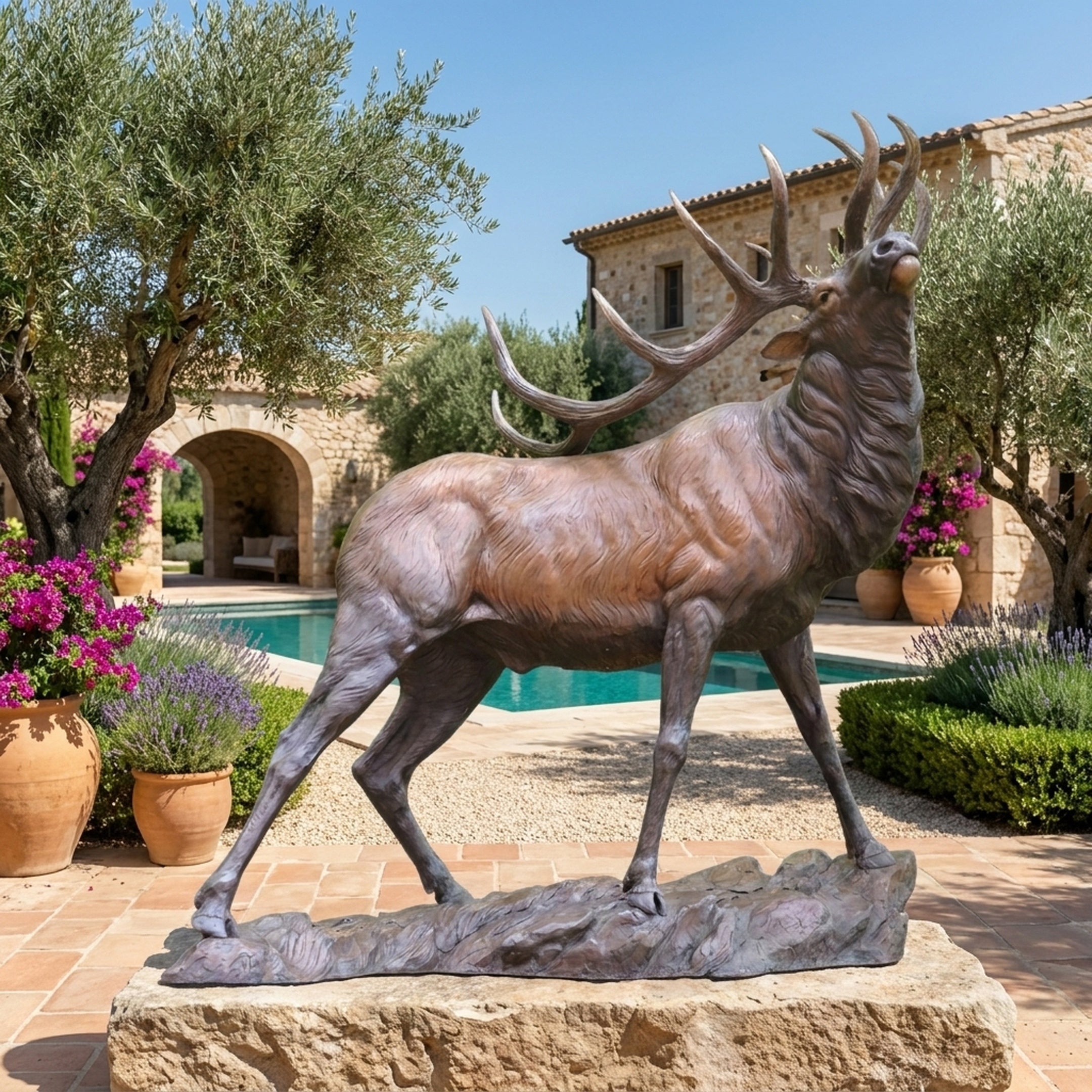 Life-Size Bugling Bull Elk Bronze Sculpture by Giant Sculptures, 230cm, displayed on a stone plinth in a Mediterranean courtyard with olive trees and pool.