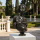 Life-Size Classical African Woman Bust Bronze Sculpture by Giant Sculptures, dark patina with braided hair and draped fabric, on a white plinth in a garden terrace.