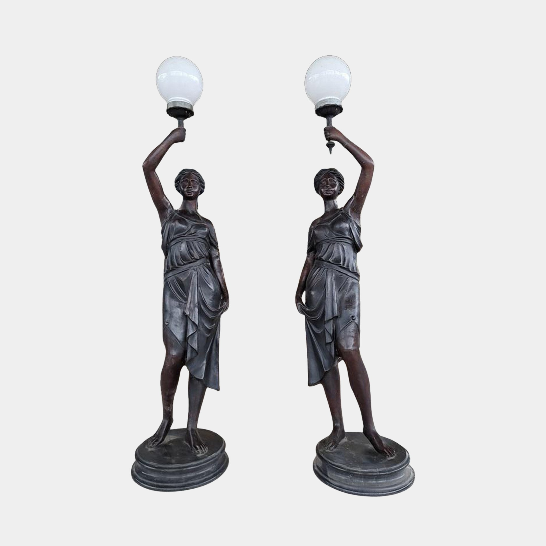 Pair of Giant Sculptures Life-Size Classical Draped Female Figure Lamp Bronze Sculptures in dark patina, each raising a white globe lamp overhead, on round bases.