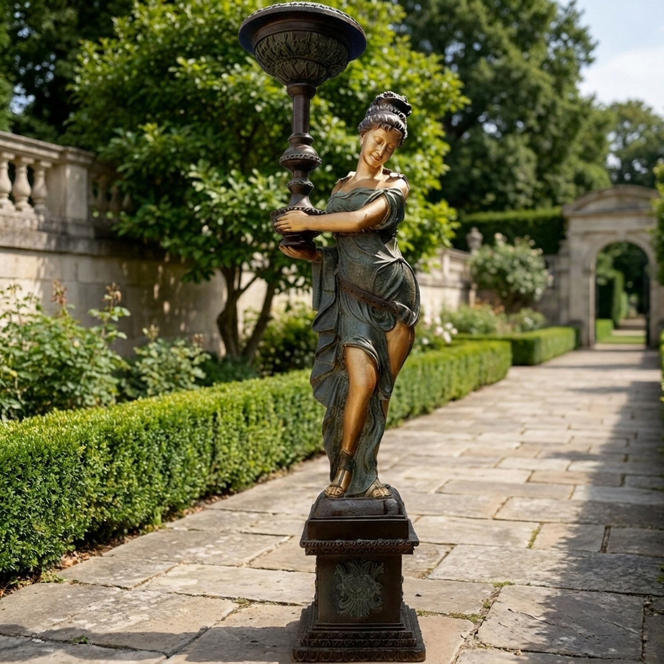 Life-Size Classical Goddess Lamp Bearer Bronze Sculpture by Giant Sculptures, 240cm verdigris figure holding a torch lamp, on a plinth along a garden path.