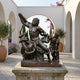 Life-Size Classical Laocoon and Sons Bronze Sculpture by Giant Sculptures on a stone plinth in an arched Mediterranean courtyard with olive trees.