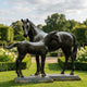 Life-Size Classical Mare and Foal Bronze Sculpture by Giant Sculptures shown in a formal garden, with the dark patinated foal in profile beside the mare.