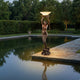 Giant Sculptures Life-Size Classical Mermaid Lamp Bearer Bronze Sculpture 210cm beside a reflective garden pool, holding an illuminated frosted shell bowl aloft at dusk.
