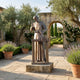 Life-Size Classical Saint Joseph the Worker Bronze Sculpture by Giant Sculptures on a granite plinth in a Mediterranean courtyard with lavender and olive trees.