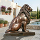 Giant Sculptures Life-Size Classical Seated Lion Bronze Sculpture 260cm in warm brown patina, shown in profile beside a poolside terrace with potted lavender.