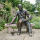 Life-Size Classical Seated Man Reading Bronze Sculpture by Giant Sculptures, 210cm Victorian figure on a granite bench with a small duck, in a rose garden.