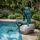 Life-Size Classical Seated Mermaid on Rock Bronze Sculpture by Giant Sculptures with verdigris patina, posed on a stone boulder beside a poolside garden.