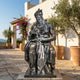 Life-Size Classical Seated Moses Bronze Statue by Giant Sculptures with dark patina, displayed on a stone courtyard beside olive trees and terracotta pots.