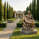 Life-Size Classical Seated Pietà Bronze Sculpture by Giant Sculptures with golden-brown patina on a stone base in a cypress-lined garden near a chapel.