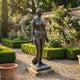 Life-Size Classical Standing Nude Female Bronze Sculpture by Giant Sculptures with dark brown patina on a stone plinth in a walled rose garden.