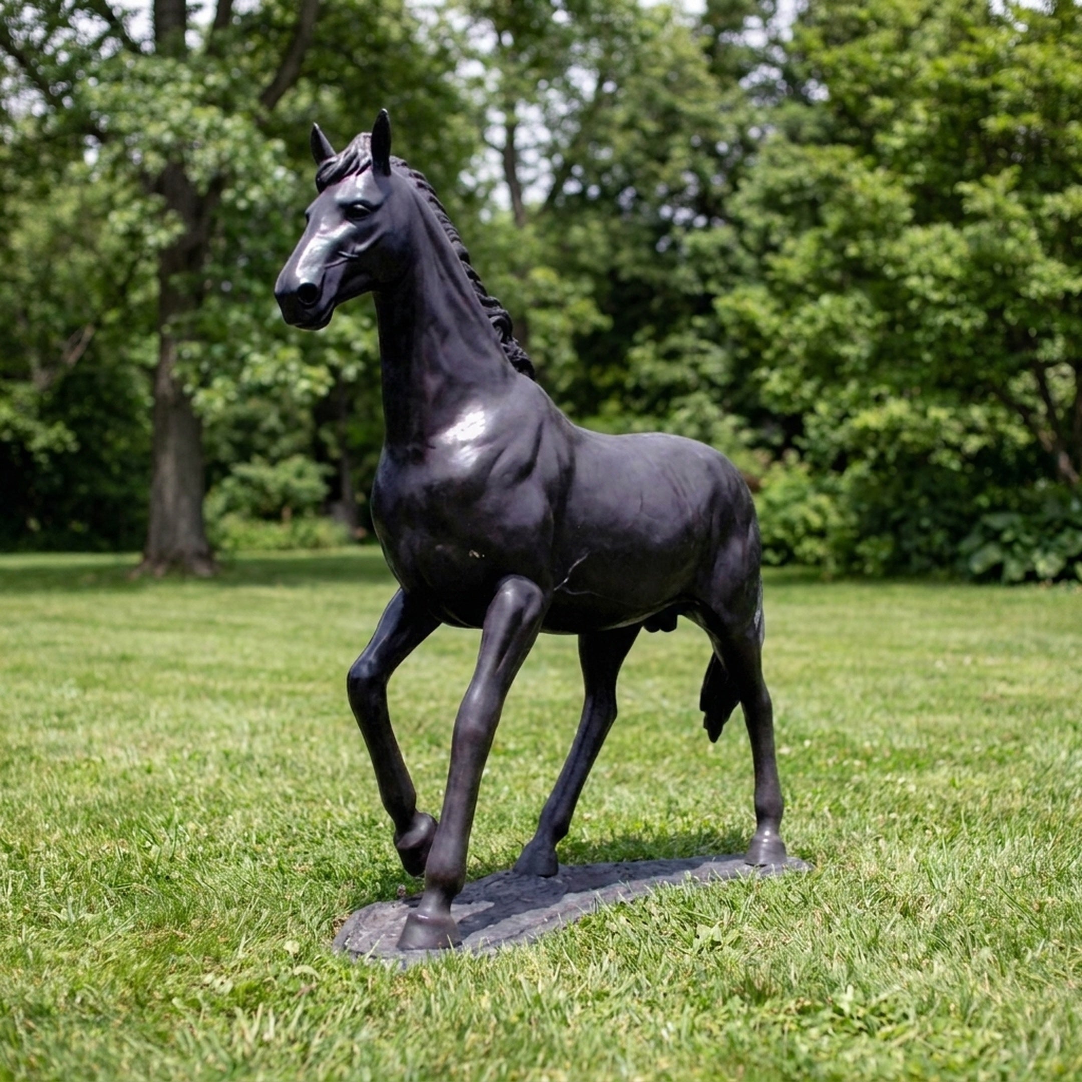 Life-Size Classical Trotting Horse Bronze Sculpture by Giant Sculptures shown on grass with raised right foreleg, dark patina finish, and trees behind.