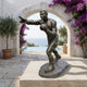 Life-Size Contemporary Boxer Bronze Sculpture by Giant Sculptures, mid-punch with left arm extended, displayed on a stone plinth by an archway and pool.