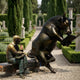 Life-Size Contemporary Bull and Man Reading Bronze Sculpture by Giant Sculptures, dark patinated rearing bull and golden seated reader sharing a bench in a formal garden.
