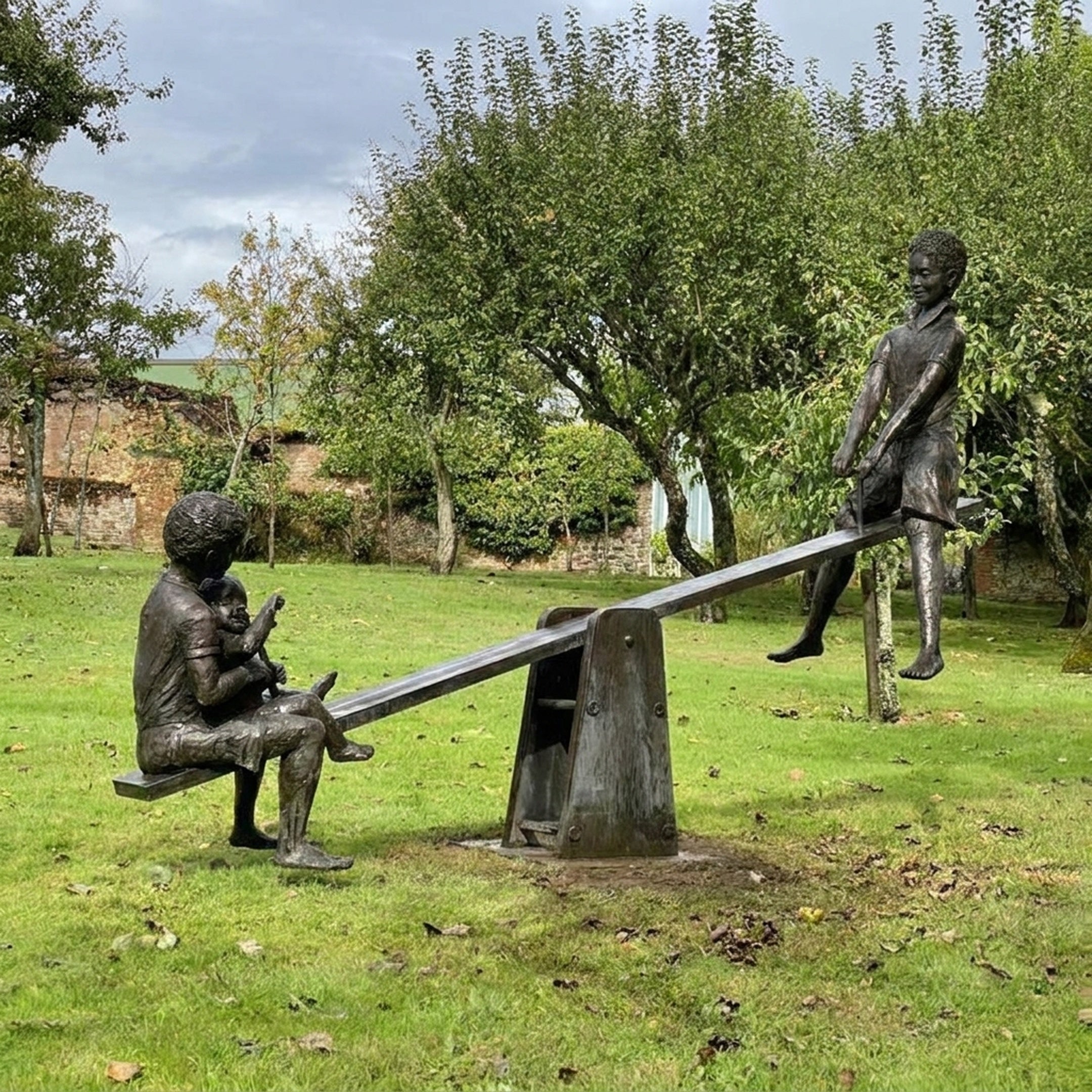 Life-Size Contemporary Children on Seesaw Bronze Sculpture by Giant Sculptures, dark patina figures mid-play on a garden lawn with trees behind.