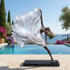 Life-Size Contemporary Dancing Female Figure Bronze Sculpture 220cm by Giant Sculptures, dancer on tiptoe with white sweeping dress, displayed poolside by the sea.