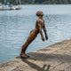 Life-Size Contemporary Diver Bronze Sculpture by Giant Sculptures, nude male figure leaning forward on a timber dock edge at the water, warm reddish-brown patina.