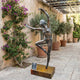 Life-Size Contemporary Female Dancer Bronze Sculpture by Giant Sculptures in arabesque pose on a bronze plinth, displayed in a stone courtyard with bougainvillea.