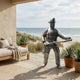 Life-Size Contemporary Fireman Bronze Statue by Giant Sculptures displayed on a coastal patio with daybed and agave planters, overlooking dunes and ocean.