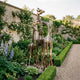 Life-Size Contemporary Giraffe Family Group Bronze Sculpture by Giant Sculptures, 250cm, displayed in a walled rose garden beside a gravel path and box hedging.