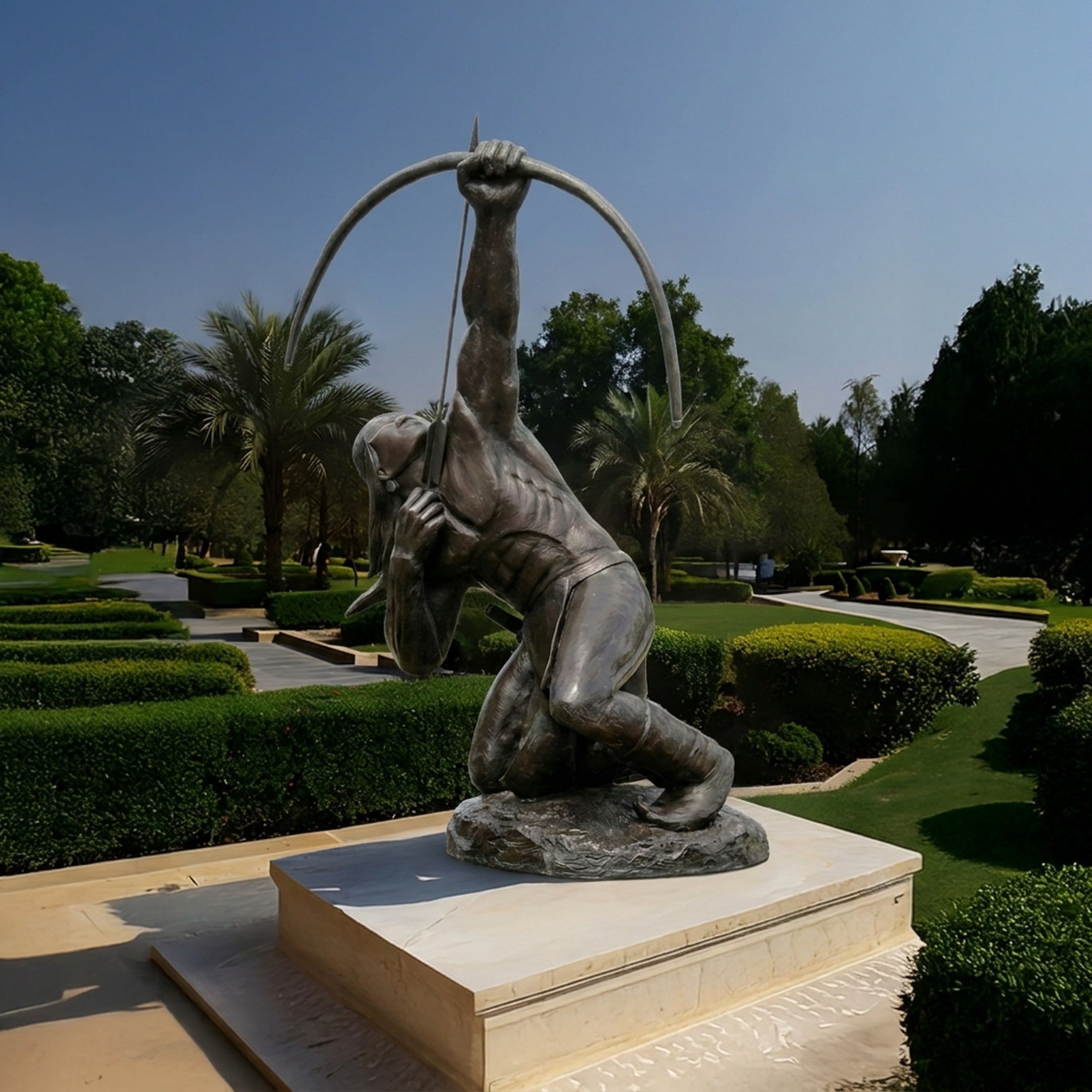 Life-Size Contemporary Kneeling Archer Bronze Sculpture by Giant Sculptures, dark patina figure drawing a bow overhead, on a pale stone plinth in a garden.