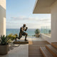 Life-Size Contemporary Kneeling Boxer Bronze Sculpture by Giant Sculptures on a seaside terrace with agave planters, glass railing, and ocean views.