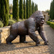 Life-Size Contemporary Knuckle-Walking Gorilla Bronze Sculpture by Giant Sculptures in side profile on gravel path beside a stone wall lined with cypress trees.