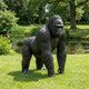 Life-Size Knuckle-Walking Gorilla Bronze Sculpture by Giant Sculptures in dark patina, shown on a lawn beside a pond with mature trees behind.