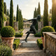 Life-Size Contemporary Male Runner Bronze Sculpture by Giant Sculptures with dark patina, mid-sprint pose on a stone plinth in a cypress-lined garden path.