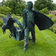 Life-Size Contemporary Man and Eagle Bronze Sculpture by Giant Sculptures, verdigris-finished figure in a flowing coat with an eagle rising from a trunk, set on a garden lawn.