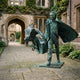 Life-Size Contemporary Man and Eagle Bronze Sculpture by Giant Sculptures, verdigris patina figure with eagle rising from a trunk, shown in an ivy-covered courtyard.