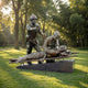 Life-Size Contemporary Military Nurse and Wounded Soldier Bronze Sculpture by Giant Sculptures on a granite plinth in a sunlit park setting.