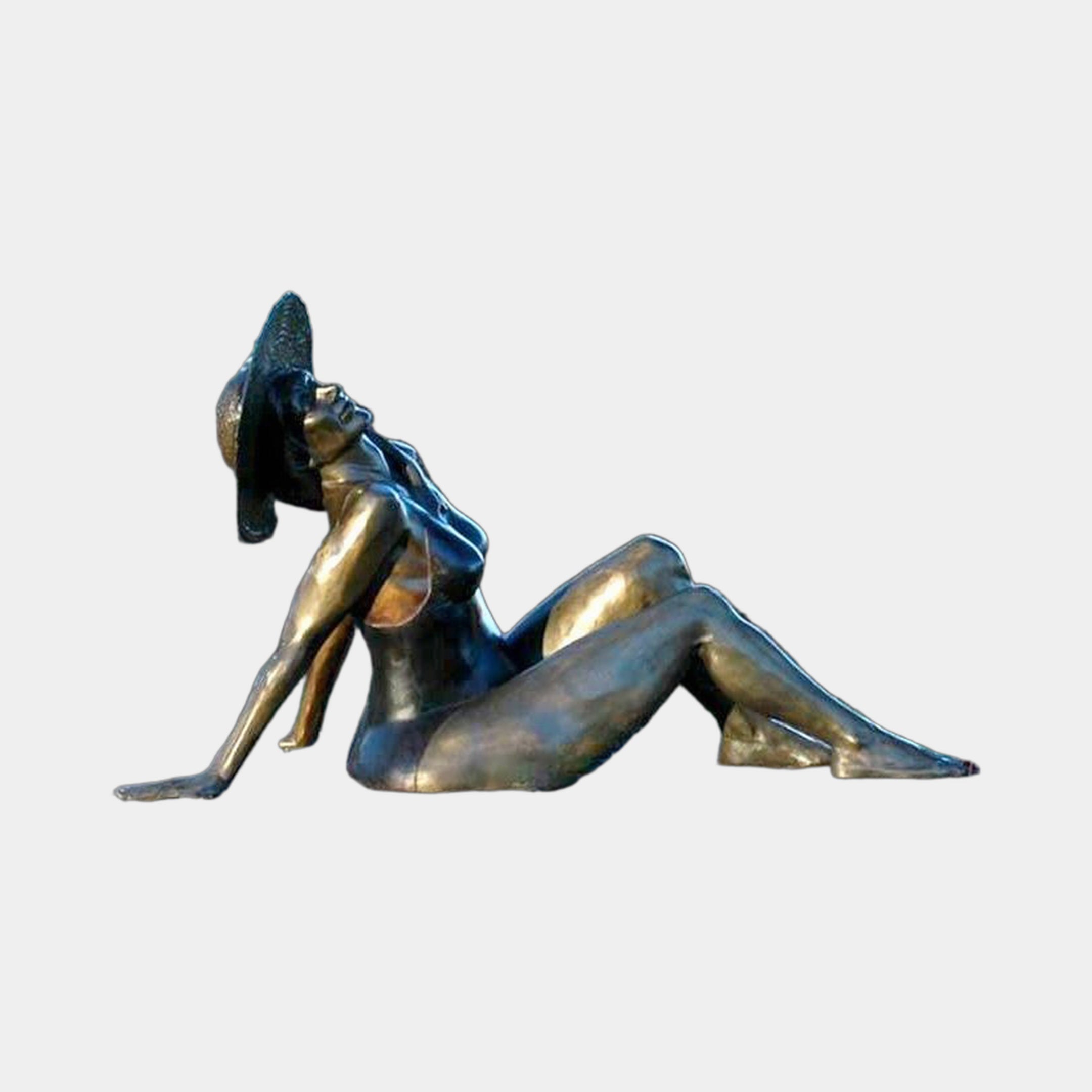 Life-Size Contemporary Reclining Woman Bronze Sculpture by Giant Sculptures, shown in side profile with raised knees, wide-brimmed hat, and warm golden-brown patina.