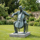 Life-Size Contemporary Seated Cellist Bronze Sculpture 190cm by Giant Sculptures with verdigris patina, shown on a stone plinth in a garden lawn setting.