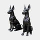 Life-Size Contemporary Seated Doberman Pair Bronze Sculpture by Giant Sculptures, 100cm, in glossy black with alert cropped ears, shown on a plain background.