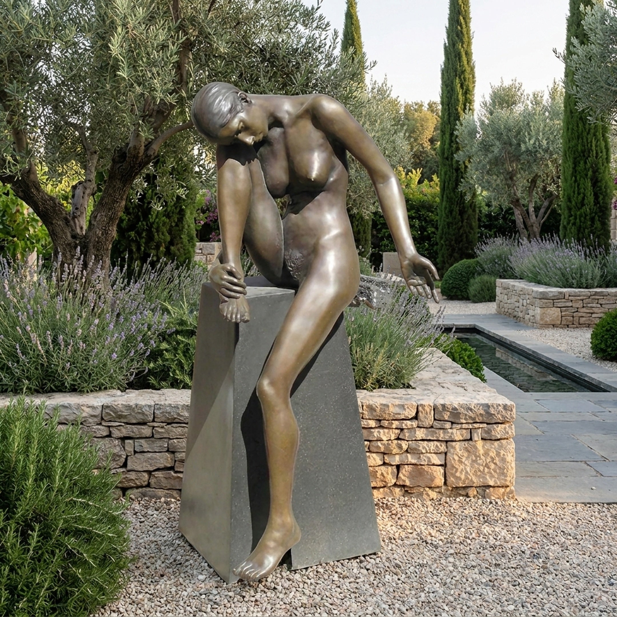 Life-Size Contemporary Seated Female Figure Bronze Sculpture by Giant Sculptures on a dark granite plinth in a Mediterranean garden with lavender and cypress.