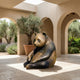 Life-Size Contemporary Seated Panda Bronze Sculpture by Giant Sculptures in a sunlit arched courtyard with olive trees and lavender.
