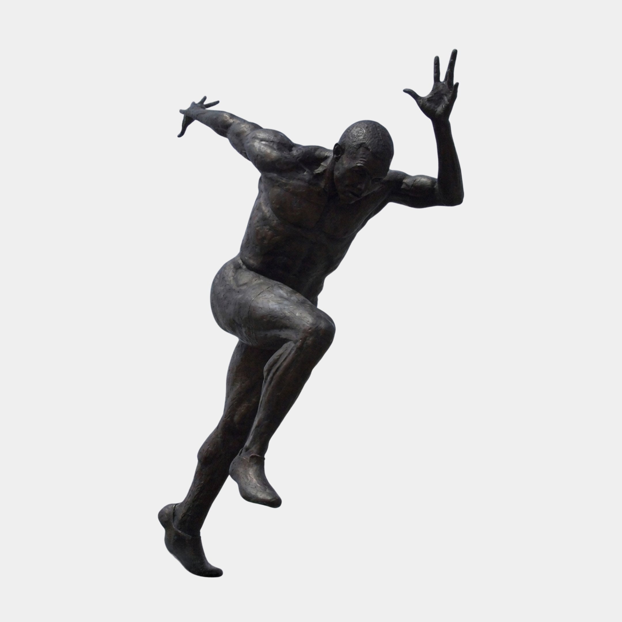 Life-Size Contemporary Sprinting Male Figure Bronze Sculpture by Giant Sculptures, mid-stride with arms flung wide and dark patina finish, on a plain background.