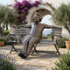 Giant Sculptures Life-Size Wild-Haired Man on Bench Bronze Sculpture with arms spread along the backrest, set on a stone patio with lavender and olive trees.