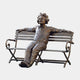 Life-Size Contemporary Wild-Haired Man on Bench Bronze Sculpture by Giant Sculptures, seated with arms spread along the backrest, warm brown patina, on plain background.